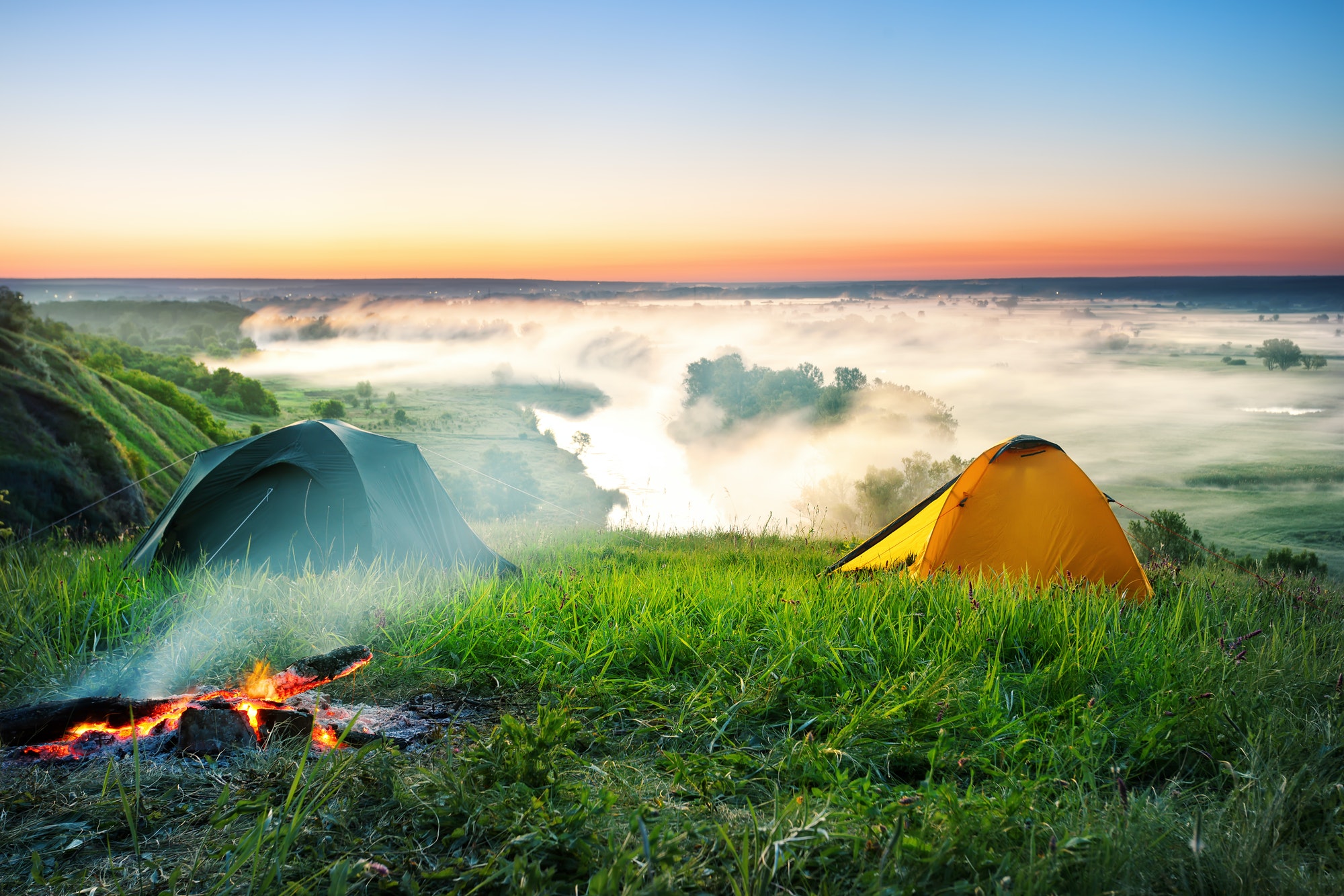 Tent camping on hill over misty river