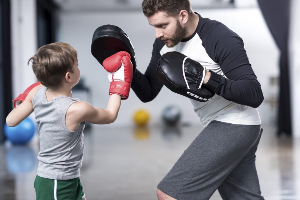 young boy boxer practicing punches with coach